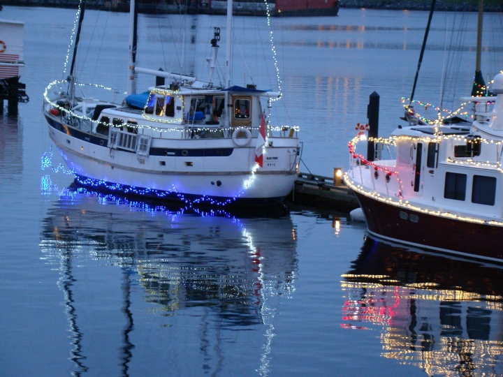 Boats in Victoria’s Inner Harbour, decorated with Christmas lights reflecting in the water